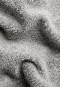 Gray, textured towel with a soft, plush surface, displaying folds and subtle variations in shading across its fabric.