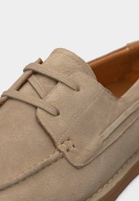 Μπεζ casual παπούτσι από σουέντ με ραφτενές λεπτομέρειες και κορδόνια που ταιριάζουν, διαθέτει εσωτερικό από λείο δέρμα και ελαστική σόλα.