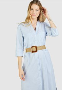Hellblau gestreiftes Hemdkleid mit langen Ärmeln, Knopfdetails, zwei vorderen Taschen und einem gewebten beigen Gürtel mit quadratischer Schnalle.
