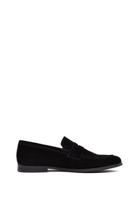 Mocassins en suede noir avec une semelle plate, présentant un design surpiqué et un accent de bande sur le cou-de-pied. Texture lisse, silhouette minimaliste.