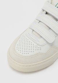 Valge toss, millel on sileda naha ja seemisnaha segu, perforatsioonidega varbarea, kolm takjakinnitusega rihma ning tekstuurse kummist tallaga.