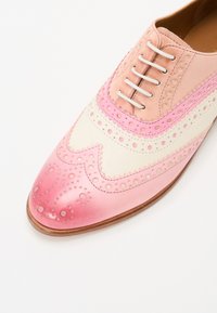 Scarpa in pelle caratterizzata da colori rosa e crema, design perforato e bordi scallop. Chiusura tradizionale con lace-up. Texture liscia.