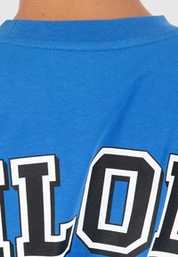 Camiseta de algodón azul con un estampado gráfico de texto en blanco y negro. Escote de cuello redondo con una textura suave y mangas cortas.