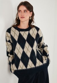Maglione lavorato a maglia con un motivo a diamante blu navy, crema e oliva, colletto girocollo e vestibilità comoda. Tessuto testurizzato con polsini e orlo a coste.