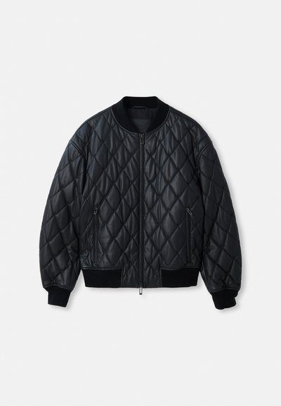 Juodas paklijuotas bomberis su apvaliomis apykaklėmis, priekiniu užtrauktuku ir perdirbto megztinio rankogaliais bei apačia. Pagamintas iš lygaus, lengvo medžiagos.