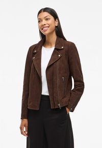 Brun semsket skinnjakke med notched krave, sølvfarget hardware, asymmetrisk frontglidelås og glidelåslommer på siden.