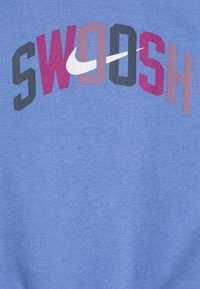 Helehelesinine dress, millel on sõna "SWOOSH" mitmevärvilistes tähtedes, kusjuures kirja vahel on silmatorkav valge Nike logo.