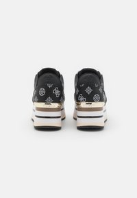 Mustat platteritossut, joissa on valkoisia ja kultaisia yksityiskohtia, tekstuurilla varustettu pinta ja kiiltävä pinta. Paksu pohja vaakasuorilla raidoilla.