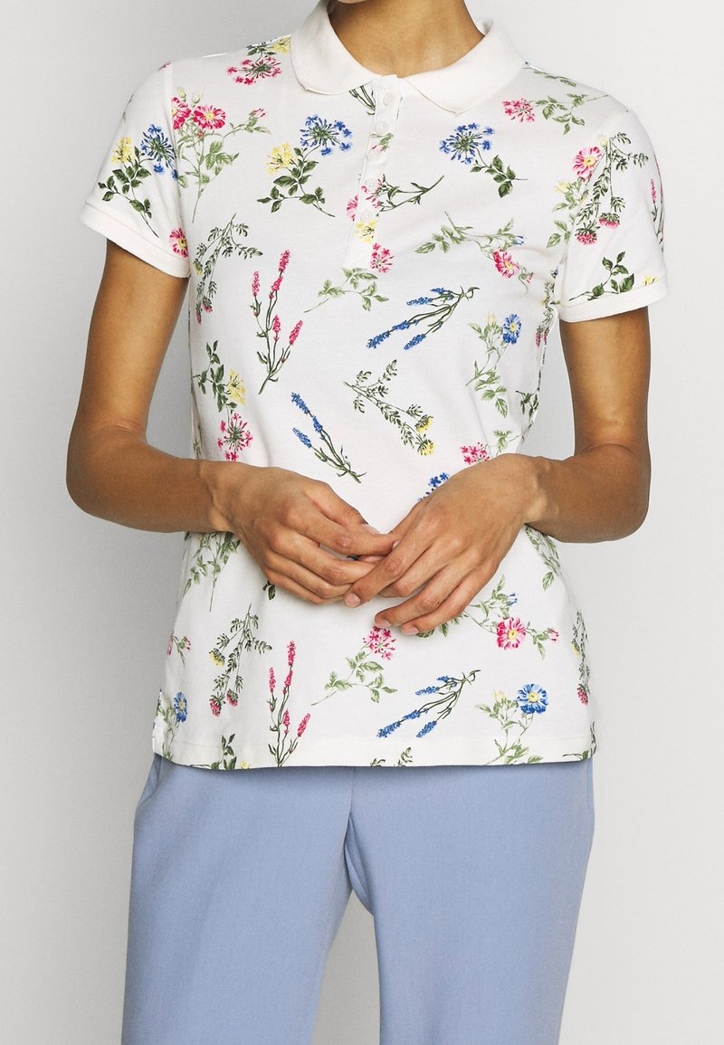 Kurzarm-Poloshirt aus weißer Baumwolle mit einem floralen Muster in Pink, Blau und Gelb. Mit kragenförmigem Ausschnitt und slim fit.