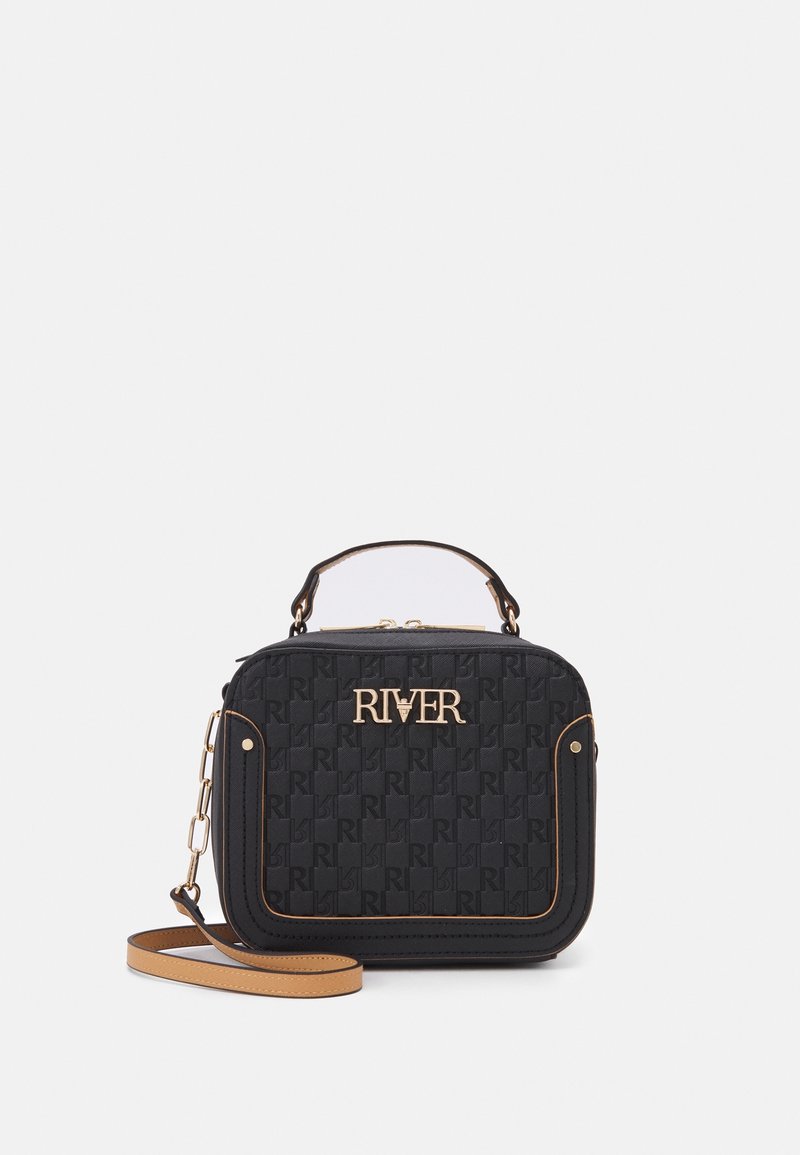 Black quilted shoulder bag with gold logo, chain and leather strap, featuring a boxy shape and contrasting tan accents.