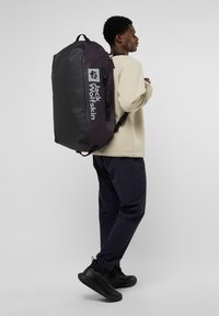 Zaino Jack Wolfskin nero e viola con spallacci regolabili, dotato di un ampio scomparto principale e stampa del logo sul lato. Finitura opaca.