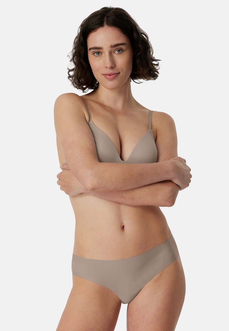 Bra and underwear set in a light beige hue. The bra features a smooth, subtle V-neck design with adjustable straps; the underwear is seamless, mid-rise.