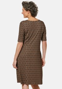 Braunes Kleid mit kurzen Ärmeln, das ein geometrisches Muster aus Dreiecken aufweist. Glatte Textur, knielang und runder Ausschnitt.