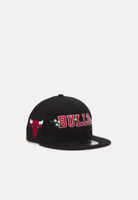 Gorra snapback negra con bordado rojo "BULLS" y acentos florales, presentando un logo de toro rojo en la parte frontal y un diseño de visera plana.