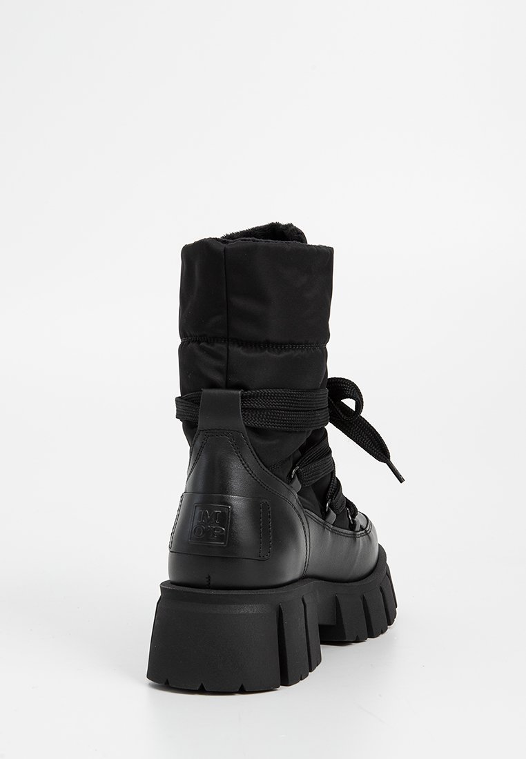 Schwarze Knöchelstiefel mit gepolstertem Obermaterial, Lederdetails, runder Zehenform und dicker Gummisohle; ausgestattet mit Schnürsenkeln und einem Logo an der Ferse.