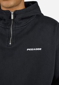 Zwarte sweatshirt met rits gemaakt van een katoenmix, met een zilveren rits en het witte 'PEGADOR' logo geborduurd op de borst.