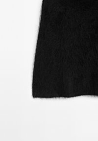 Svart fluffigt tyg med täta, mjuka fibrer visas mot en enkel vit bakgrund, med fokus på textur och kantdetaljer.