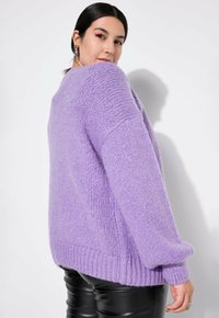 Lila übergroßer Pullover mit einem strukturierten Strickmuster und gerippten Bündchen und Saum. Getragen mit schwarzen Lederhosen.