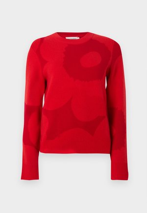 Raudonas megztinis su tekstūruotu mezgimu, apvalia iškirpte ir ryškiais abstrakčiais raštais tamsesnėmis raudonomis spalvomis. Rankogaliai ir apačia su raišteliais.