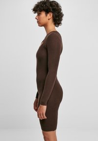 Abito a maniche lunghe marrone a coste con silhouette aderenza, scollo rotondo e orlo a ginocchio. Realizzato in morbido materiale a maglia.