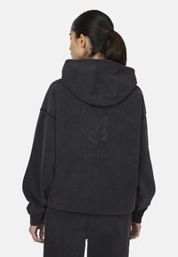 Felpa oversize grigia scura con un ampio cappuccio, caratterizzata da una grafica di una farfalla e testo in rilievo "Good For Nothing" sul retro. Tessuto morbido.