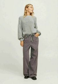Gray knit sweater with balloon sleeves paired with loose-fitting, high-waisted dark gray jeans and black chunky shoes.
