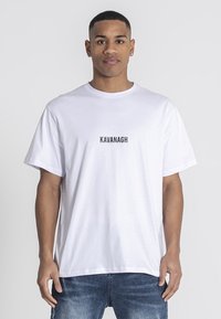 Camiseta de algodón blanca de manga corta, con el texto "KAVANAGH" en negro en el frente. Corte relajado y diseño sencillo.