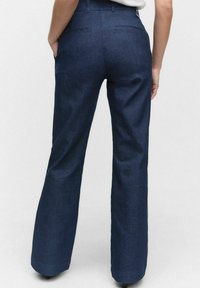 Szerokie spodnie z ciemnoniebieskiego dżinsu o gładkiej fakturze, posiadające dwie tylne kieszenie i fason z wysokim stanem.