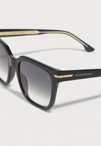 Μαύρα τετράγωνα γυαλιά ηλίου με φακούς διαβαθμισμένου σκοταδιού, χρυσή επένδυση στους βραχίονες και το λογότυπο "Victoria Beckham" στο πλαϊνό σκέλος.