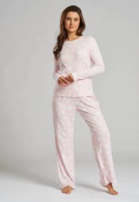 Light pink long-sleeve pajama set with star pattern, soft fabric, relaxed fit, and flared pant legs with scalloped hems.