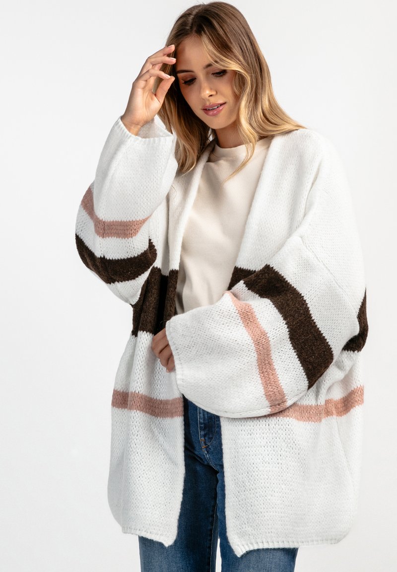 Gruby sweter kardigan w kolorze białym z szerokimi rękawami, z brązowymi i różowymi poziomymi paskami. Miękka faktura; design z otwartym przodem.