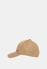 Cappellino da baseball beige con visiera curva, tessuto texture e un piccolo logo nero sulla parte anteriore; presenta una parte superiore arrotondata e una cintura regolabile.
