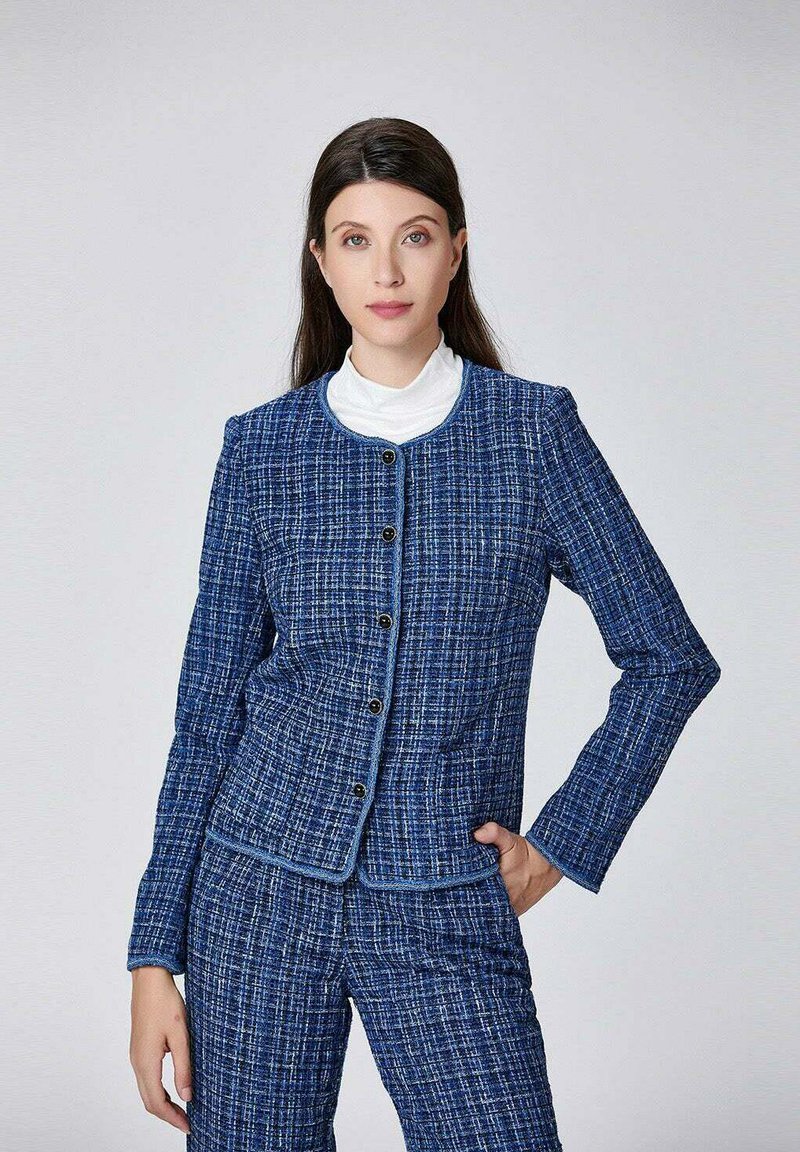 Veste en tweed bleu marine avec un col rond, fermeture à boutons et motif texturé, associée à un pantalon assorti. Coupe lisse et structurée.