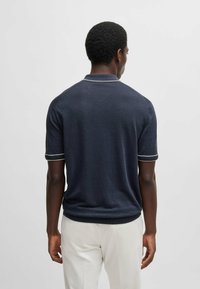 Granatowa koszulka polo z krótkim rękawem, z rypsowym kołnierzykiem i mankietami, wykończona białym paskiem. Miękka dzianina o dopasowanym kroju i czystych liniach.