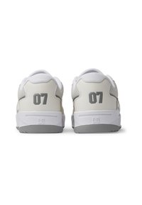Ett par vita och ljusgrå sneakers med en slät läderöverdela, vadderad krage och en djärv grå "07" på hälen.