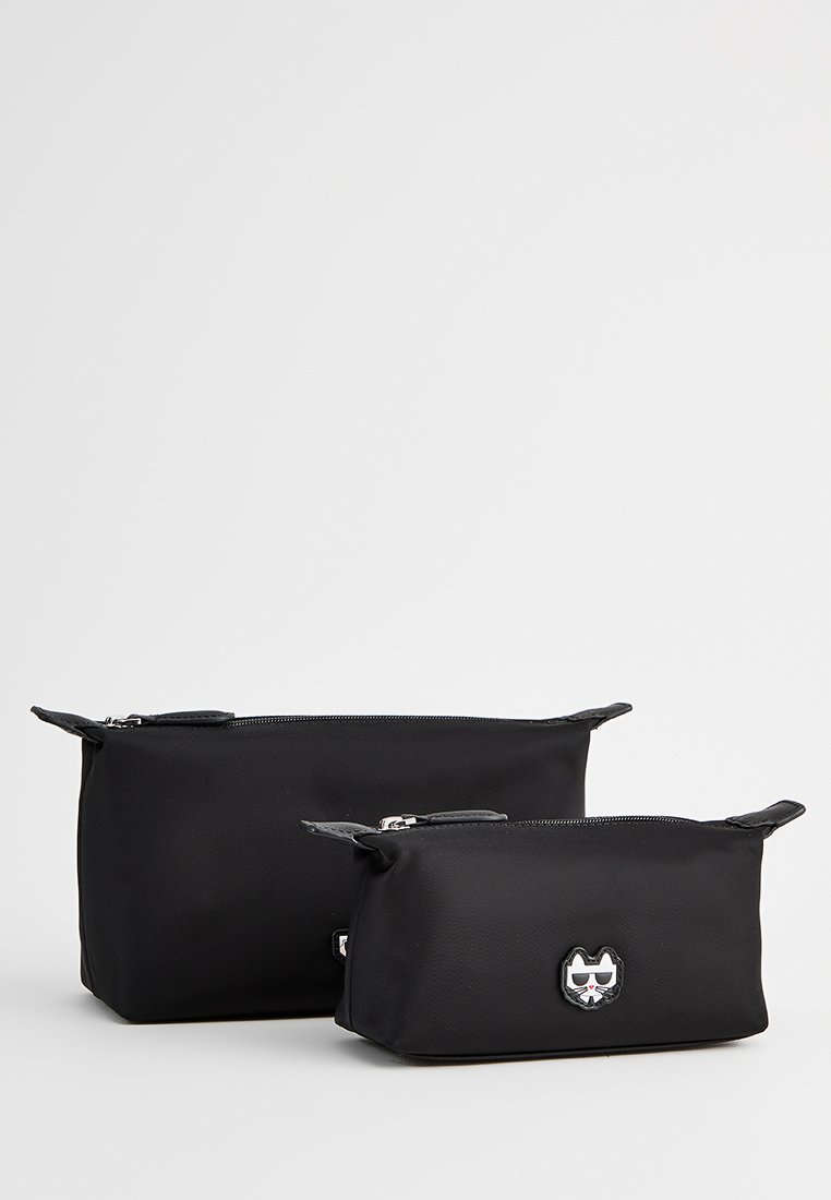 Due borse nere in nylon con chiusure a zip. La borsa più grande presenta un logo a forma di faccia di gatto, entrambe hanno forme arrotondate e texture lisce.