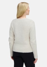 Helles beiges Strickpullover mit weichem, strukturiertem Finish. Verfügt über lange Ärmeln, einen abgerundeten Ausschnitt und einen gerippten Saum.