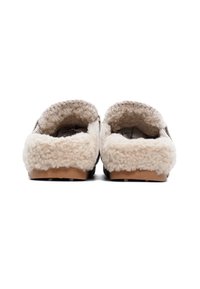 Paio di pantofole beige foderate in shearling con suole in gomma, viste dal tallone su sfondo bianco.
