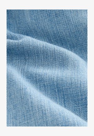 Helles blauer Jeansstoff mit glatter Textur, der ein Fischgrätenmuster und subtile Farb- sowie Webvariationen zeigt.