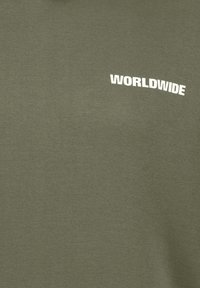 Olive green cotton T-shirt featuring white "WORLDWIDE" text on the front, with a regular fit and soft texture.