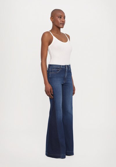 Donkerblauwe flared jeans met een klassieke vijf-pocket ontwerp en een lichte wassing, gecombineerd met een witte tanktop. Soepele textuur, hoge taille.