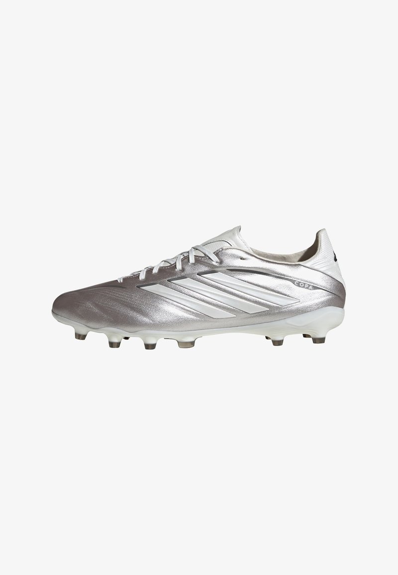 Chaussure de football Adidas Copa argentée avec des rayures blanches, des lacets et des crampons sur un fond blanc propre.