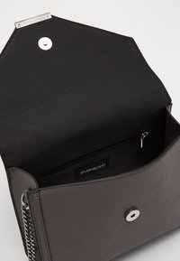 Borsa sintetica grigia con texture, dotata di uno sportello aperto, chiusura a scatto, tasca interna con zip e etichetta del marchio all'interno.