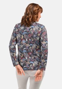 Maglietta a maniche lunghe con un motivo floreale scuro in rosso, blu e crema. Presenta un collo rotondo e una silhouette aderente.