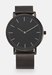Montre noire en métal avec un cadran lisse et mat et des index d'heure argentés. Elle dispose d'un bracelet en maille de couleur gris foncé, ajoutant texture et contraste.