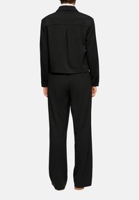 Sort, skræddersyet jakke med bagplissé og lange ærmer, kombineret med vidde bukser. Glat tekstur, minimalistisk design.