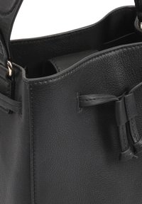 Zwarte leren handtas met een gestructureerde afwerking, voorzien van een kleine opening, smalle bandjes en gestrikte accenten aan de zijkanten.