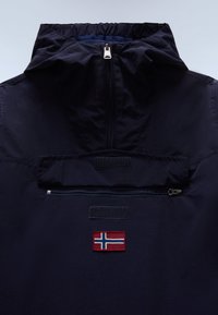 Tengerészkék dzseki magas gallérral, elején zsebbel, cipzárral és norvég zászlóval díszítve. Texturált anyag, sima felülettel.