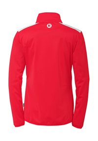 Rød jakke med lange ærmer, høj krave og hvide skulderdetaljer. Glat stof og logo på ryggen. Enkel, tætsiddende design.