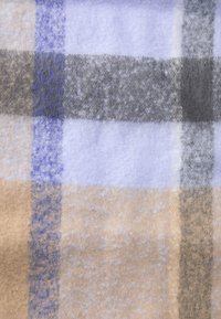 O tecido de fleece xadrez apresenta uma textura suave com tons de azul claro, bege, cinza e roxo dispostos em largas faixas alternadas.